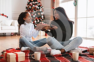 Portrait of happy black family celebrating Christmas giving present