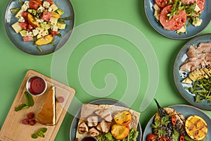 Holiday celebration table setting with food. Flat-lay of sweet cheesecake, fruit salad, meat dishes. Copy space banner.