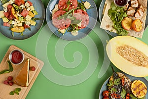 Holiday celebration table setting with food. Flat-lay of sweet cheesecake, fruit salad, meat dishes. Copy space banner.