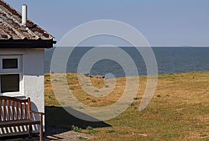 A holiday chalet with a wooden bench in front, very close to the sea at Blue Anchor in Somerset, England