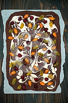 Holiday chocolate bark with dried fruits and nuts on a dark wood background. Top view. Dessert recipe for judaic holiday Tu Bishva photo