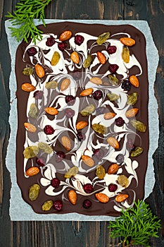Holiday chocolate bark with dried fruits and nuts on a dark wood background. Top view. Dessert recipe for judaic holiday Tu Bishva photo