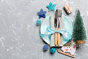 Holiday composition of Christmas dinner on cement background. Top view of plate, utensil and festive decorations. New Year Advent