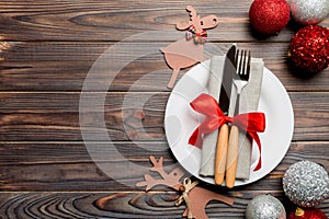 Holiday composition of Christmas dinner on wooden background. Top view of plate, utensil and festive decorations. New Year Advent