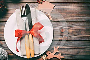 Holiday composition of Christmas dinner on wooden background. Top view of plate, utensil and festive decorations. New Year Advent