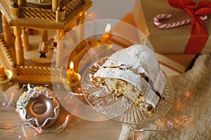 holiday composition with German Christmas cake stollen, Festive Decorations, garlands, lights, Christmas wooden carousel with