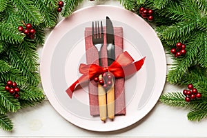 Holiday composition of plate and flatware decorated with fir tree on wooden background. Top view of Christmas decorations. Festive