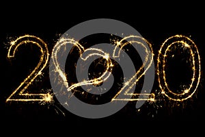 Holiday concept. Number 2020 with heart decor written sparkling sparklers isolated on black background. Overlay templatefor for