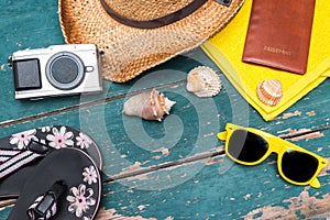 Holiday Concept: Vintage wood table with holiday accessories: Straw hat, sunglasses, flip flops, shells, vintage camera, towel and