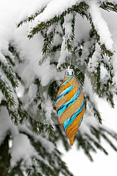 Holiday Decor: Shiny Golden Bauble on Evergreen Tree. Frost-Adorned Fir Trees Create a Winter Wonderland. Christmas Ornaments: photo