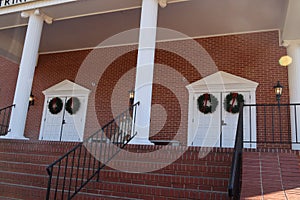 Holiday decor on white doors and brick wall distant view