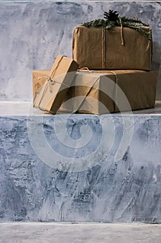 Holiday delivery boxes, parcels wrapped in brown paper, decorated and tied with rough twine, stone background with