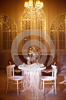 Holiday dinner table for two shined by classic chandelier light