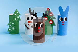 Holiday easy DIY craft idea for kids. Toilet paper roll tube toy Christmas tree, snowman, rabbit, deer on blue