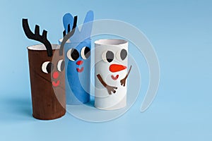 Holiday easy DIY craft idea for kids. Toilet paper roll tube toy rabbit, snowman, deer on blue background. Creative New