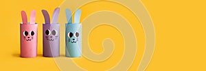 Holiday easy DIY craft idea for kids. Toilet paper roll tube toy\'s cute rabbit\'s on yellow background. Creative Easter