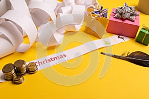 Holiday expenses concept. Long twisted christmas expenses list, presents, gifts, money coins and christmas text