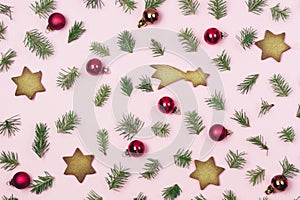 Holiday Festive Flat Lay Background with Small Green Branches Fir Tree Red Christmas Balls and Gingerbread Cookies on Pink