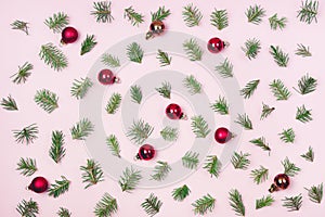 Holiday Festive Flat Lay Background with Small Green Branches Fir Tree and Red Christmas Balls on Pink Background Top View