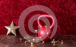 Holiday fitness, red kettlebell with gold star twinkle lights, big gold star, against a red background