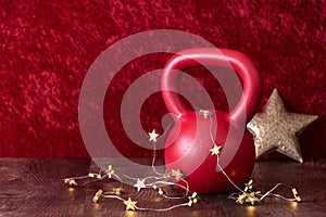 Holiday fitness, red kettlebell with gold star twinkle lights, big gold star, against a red background