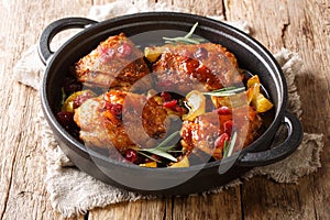 Holiday food hot baked chicken thighs with apples, cranberries and rosemary closeup in a pan. horizontal