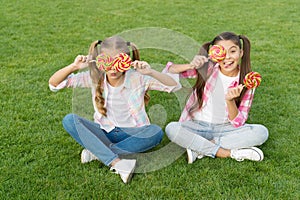 Holiday food. Sweet childhood. Happy children hold candy sit green grass. Candy shop. Lollipop treats. Candy synonym for