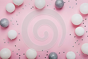 Holiday frame made of christmas balls and sequins on stylish pink table top view. Fashion background. Flat lay. Party mockup.
