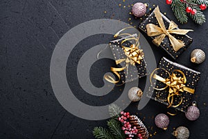 Holiday gift box or present with ribbon, golden confetti and gold baubles on black background. Magic christmas greeting card. Chri