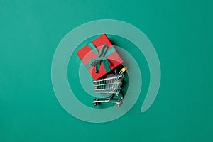 Holiday gift box in shopping cart on Paolo Veronese Green color background