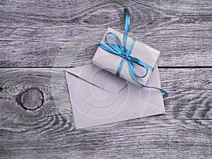 holiday gift box, tied with green ribbon, envelope of Kraft paper, blank on the wooden weathered rustic background, black and