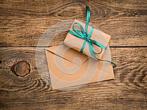 holiday gift box, tied with green ribbon, envelope of Kraft paper, blank on the wooden weathered rustic background, top view.