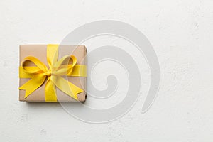 Holiday gift box wrapped in craft paper with colored bow on table background. Top view, flat lay, copy space