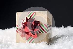 Holiday gift box wrapped in striped ribbon and shiny red bow sit