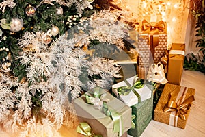 Holiday gift boxes in entourage of New Year decor Christmas tree and garland illumination
