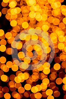 Holiday glowing gold backdrop. defocused and blurred many round yellow light on Christmas black background