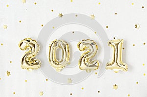 Holiday gold metallic balloon numbers 2021 and confetti on silver background