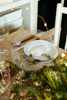 Holiday Gold place setting,  Christmas table with ornaments and natural pine branch on the livingroom home