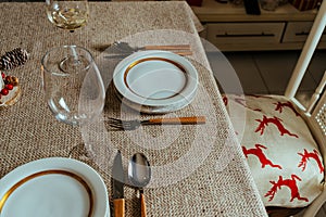 Holiday Gold place setting,  Christmas table with ornaments and natural pine branch on the livingroom home