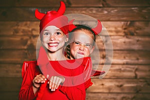 holiday halloween. funny funny sisters twins children in carnival costumes devil on wooden