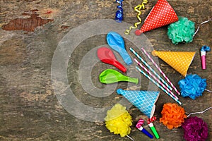 Holiday hats, whistles, balloons on old wooden background.