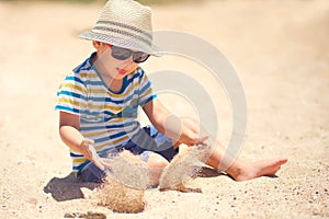 Holiday, little boy three years old fun digging in the sand at the beach