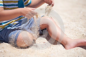 Holiday, little boy three years old fun digging in the sand at the beach