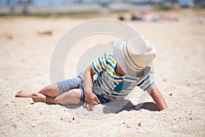 Holiday, little boy three years old fun digging in the sand at the beach