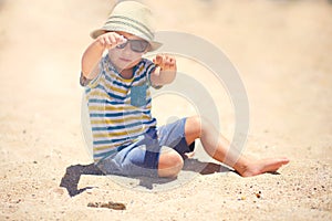 Holiday, little boy three years old fun digging in the sand at the beach