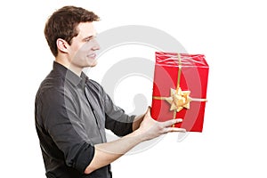 Holiday. Man giving red gift box with golden ribbon