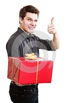 Holiday. Man giving red gift box showing thumb up