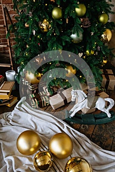 Holiday, New Year& x27;s gift boxes and wooden horse toy under decorated Christmas tree with golden baubles, garland in