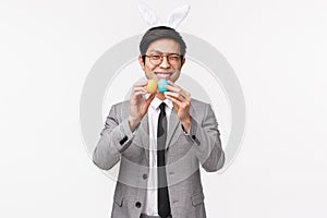 Holiday, people and celebration concept. Waist-up of silly and happy young handsome asian man in suit, rabbit ears, wink