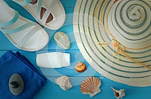 A holiday photo, a summer hat, beach sandals, sunscreen, sun glasses, scallops and souvenir pebbles.  Empty space for an inscripti